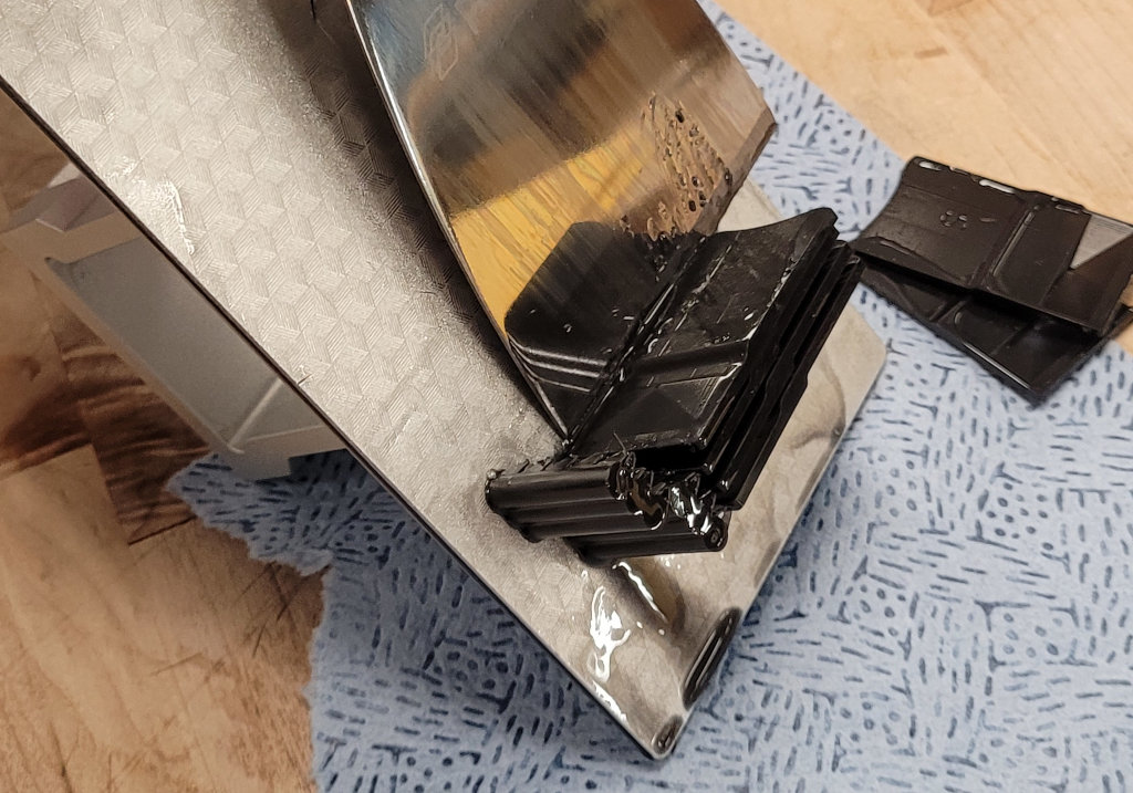 The metal scraper flat on the build plate next to the Fly Pyramid. Two pyramids have already been removed, the previously separated support cylinders are still attached to the build plate.
