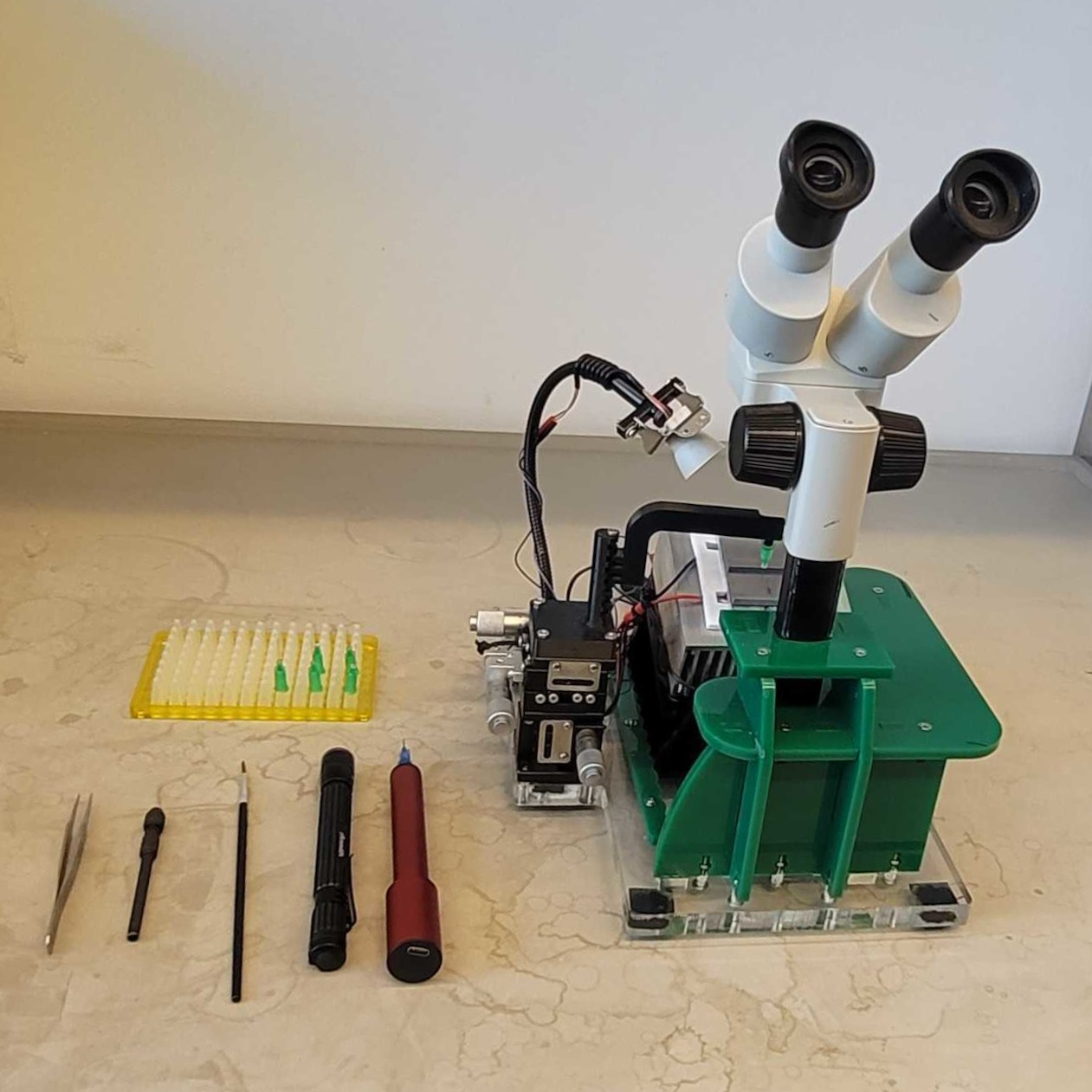 Tethering station with a dissecting microscope, cooling platform, micromanipulator, and tethering tools